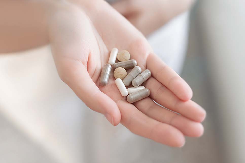 Close-up of a girl's cupped palm holding vitamins, minerals, and supplements.