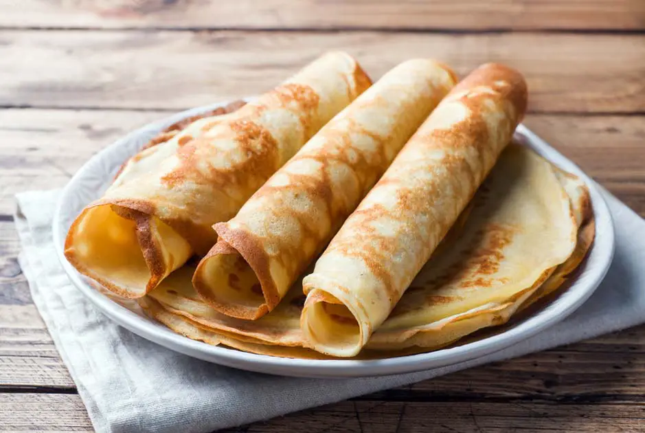 Close-up of three rolled crepes on a plate. 