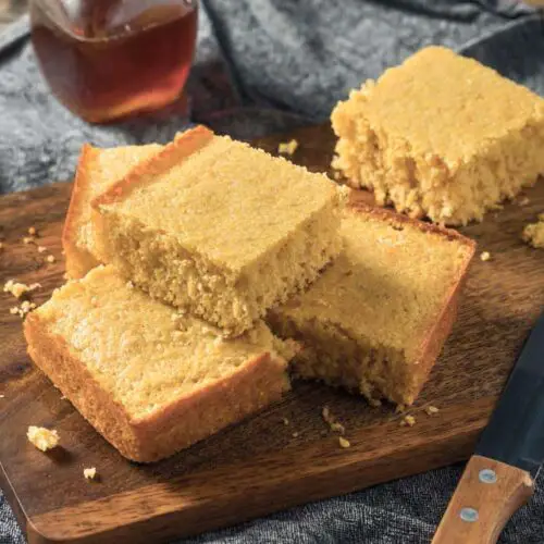 Stacks of rich vegan cornbread squares on a cutting board.