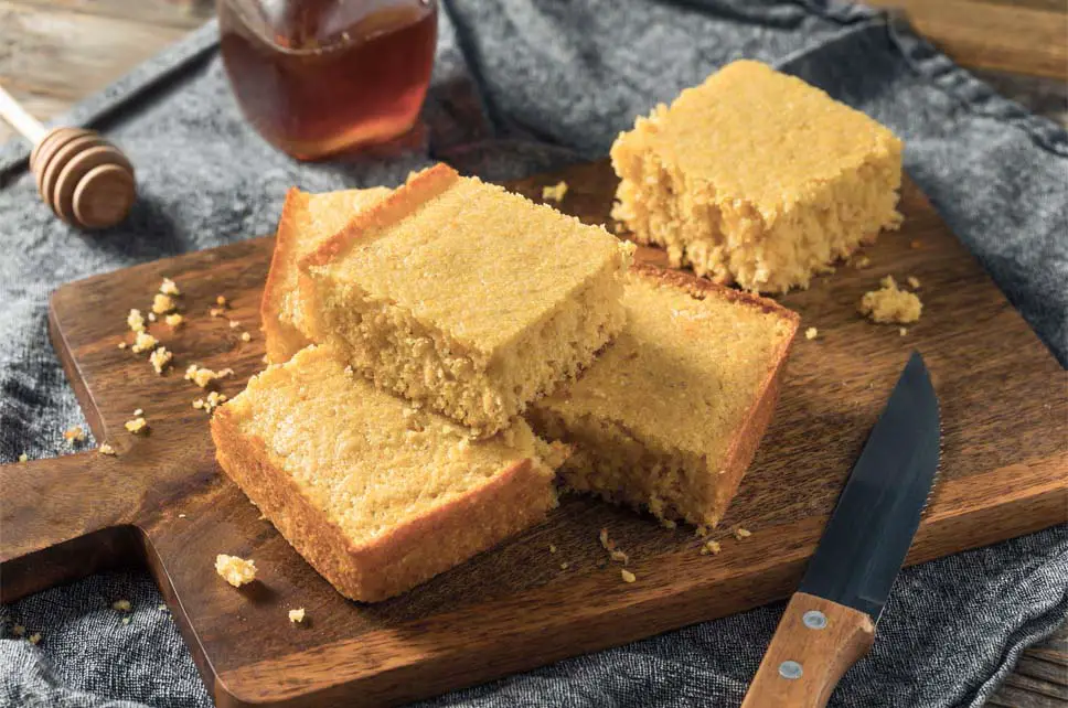 Stacks of rich vegan cornbread squares on a cutting board.