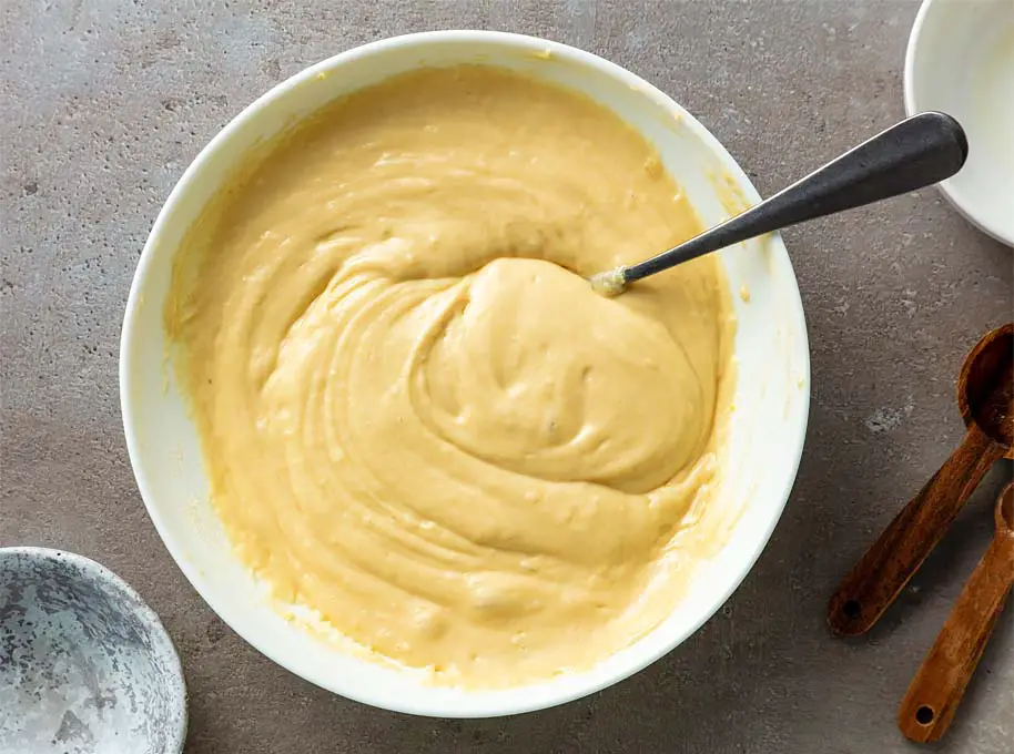 Top view of vegan cornbread batter in a mixing bowl on a granite countertop. 