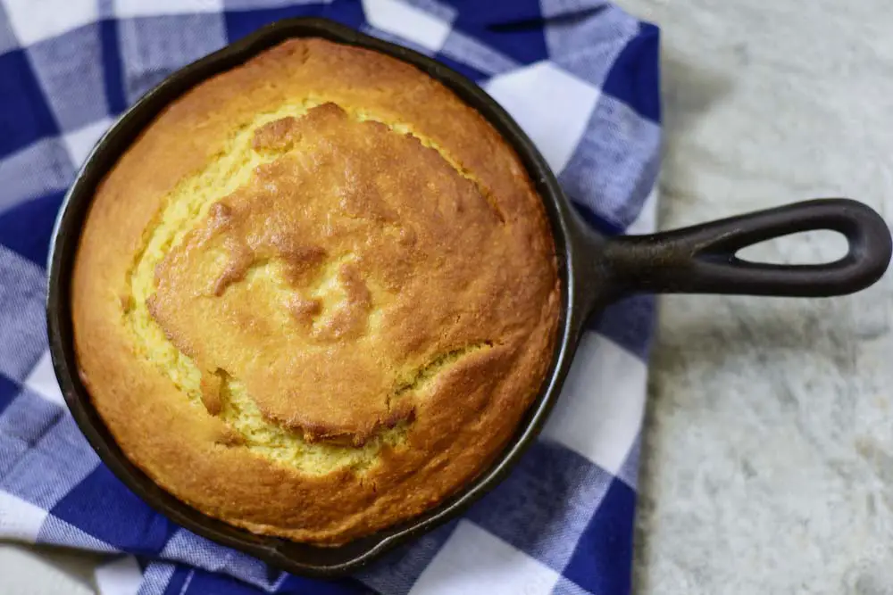 Rich and golden round of baked Himalayan Tartary Buckwheat vegan cornbread in a cast iron skillet.  