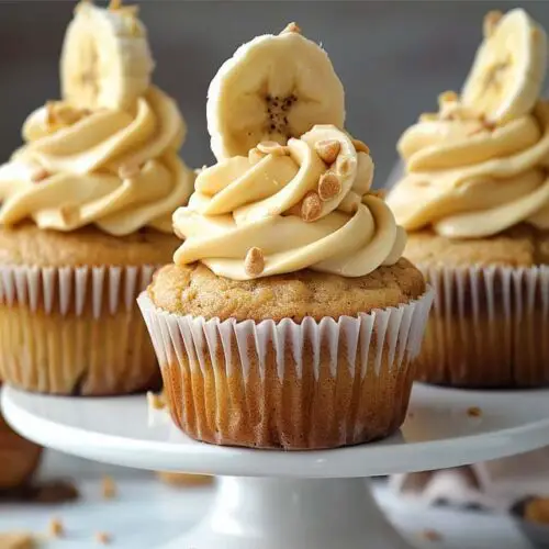 Close shot of creamy rich banana muffins topped with cream cheese frosting, banana slices, and organic walnuts.