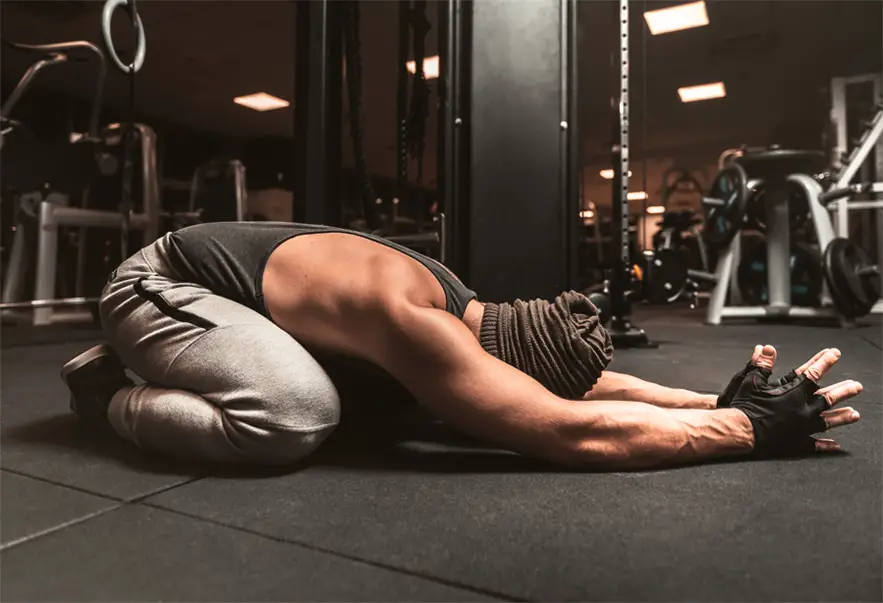 A muscular man practicing yoga postures at the gym.