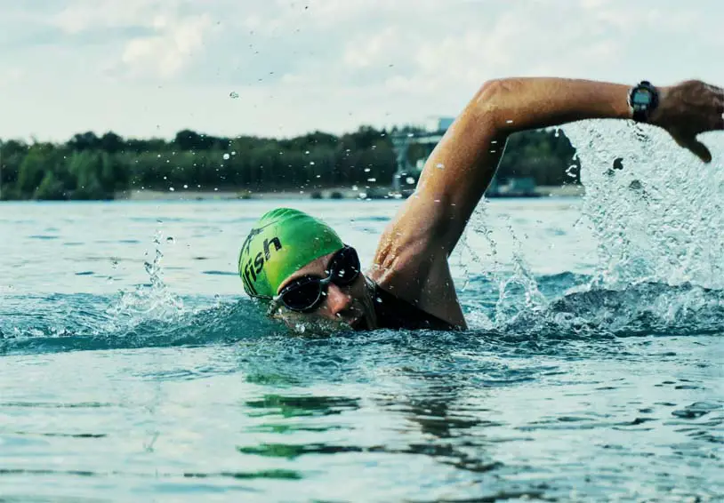 A man swimming freestyle laps in a fresh water lake.