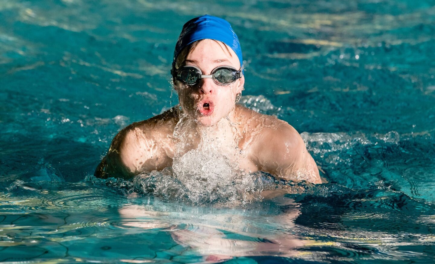 A swimmer doing laps takes a breath above water before resuming. 