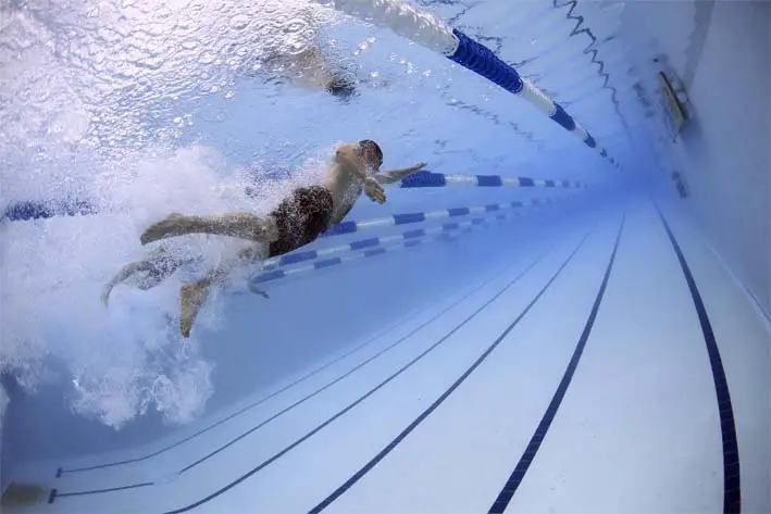 Underwater view of a man swimming freestyle laps in an Olympic pool lane.   