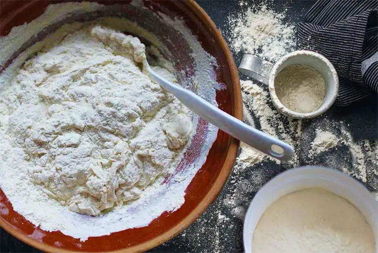 Top view of sourdough sponge starter ingredients on a floured board. 